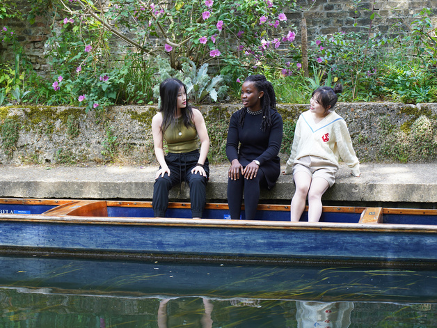 three students sitting by the river