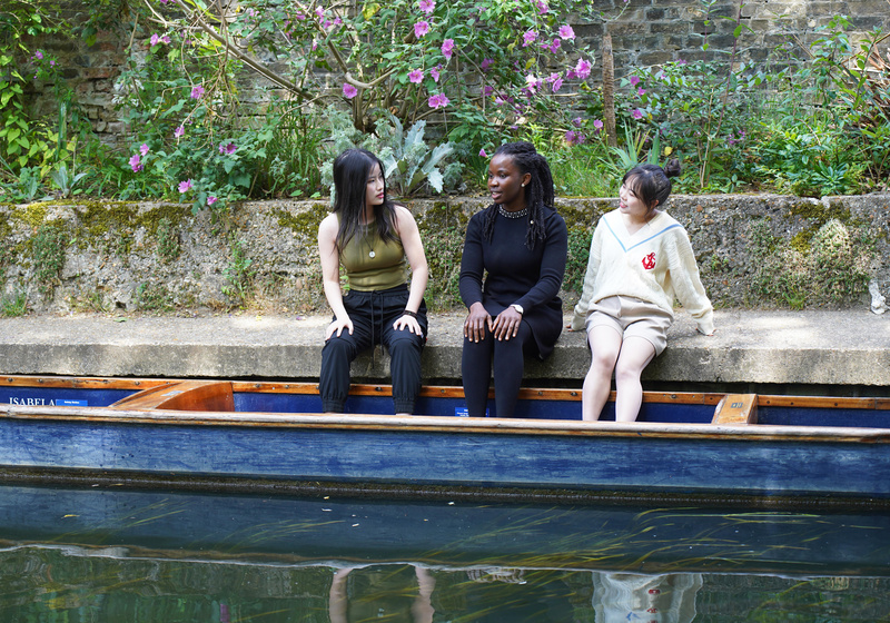 three students sitting by the river